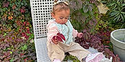 Alaïa participe au concours pour gagner de l'argent avec cette photo : toddler, child, chair, outdoor, plants, foliage, leaves, greenery, nature, pigtails, pink_shoes, jacket, pants, curly_hair, garden, pot, wall, daylight, casual_clothing, exploring