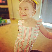 Mia joined the competition — help win amazing prizes! child, smiling, yellow_bow, romper, striped_clothing, indoor, carpet, person, cute, happy, playful, young_child, posing, light, blurred_background, home, portrait, dimple, shorts, fashion