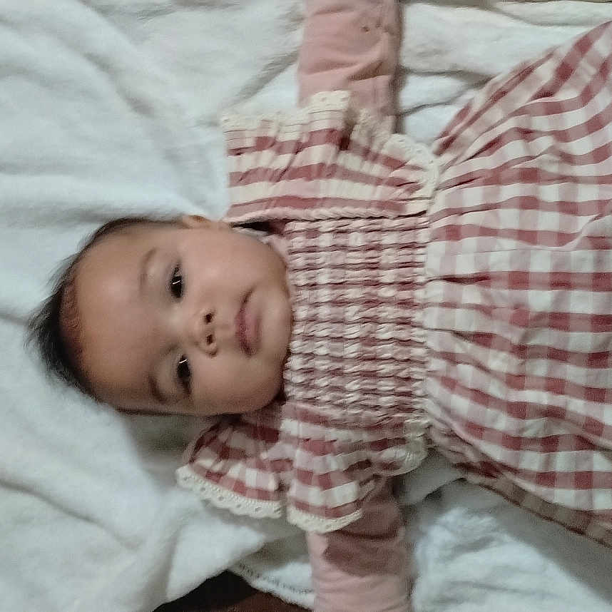 Nayllyss a rejoint le concours — aidez-le/la à gagner de superbes lots ! baby, bedding, blanket, cheeks, child, cozy, cute, dress, eyes, fabric, face, gingham_dress, human, indoors, infant, lying_down, portrait, smile, towel, wooden_floor