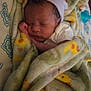 baby, blanket, sleeping, newborn, hat, bed, bedding, pattern, cozy, infant, wrapped, resting, child, person, soft, indoor, cute, peaceful, closeup, warm
