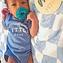 baby, infant, pacifier, blue_onesie, blanket, checkered_pattern, wooden_sign, one_month, lying_down, cute, newborn, handsome, little_dude, child, soft_texture, indoors, portrait, skin, face, sleepwear