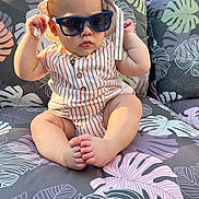 Liam joined the competition — help win amazing prizes! baby, child, sunglasses, hat, striped_clothing, romper, sitting, couch, floral_pattern, outdoor, sunlight, cute, chubby, foot, hand, face, portrait, summer, shade, relaxation
