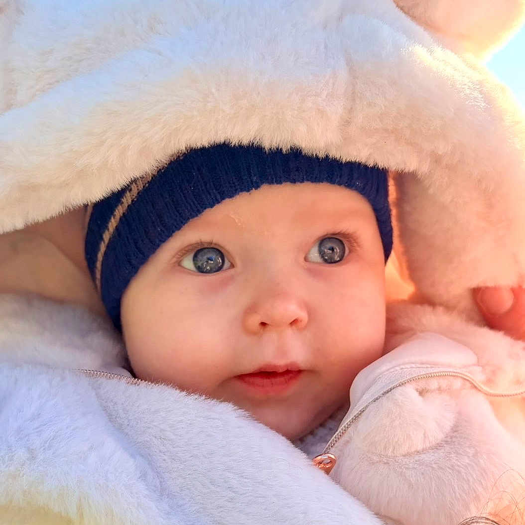 Lou a rejoint le concours — aidez-le/la à gagner de superbes lots ! baby, child, face, hat, blue_eyes, coat, fur, warm_clothing, outdoor, cute, portrait, winter, soft_texture, innocent, closeup, young, person, headwear, skin, expression