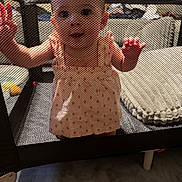 Olivia joined the competition — help win amazing prizes! baby, child, closeup, clothing, curious, cushion, cute, expression, face, floor, furniture, hand, home, indoor, infant, mesh, peach_dress, person, playpen, toy