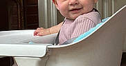 Olivia is registered to the contest to win money with this photo: baby, high_chair, smile, indoor, child, face, person, furniture, home, cozy, curious, skin, clothing, head, happy, photography, table, seat, modern, living_room