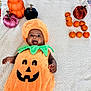 baby, pumpkin_costume, blanket, orange, decorative_pumpkin, smiling, face, child, holiday, fall, autumn, cute, happy, indoors, plush, costume, celebration, person, toddler, floor