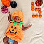 Genevieve is registered to the contest to win money with this photo: baby, pumpkin_costume, orange, decorative_pumpkins, blanket, infant, holiday, fall, autumn, cute, celebration, smiling, lying_down, festive, child, costume, indoors, soft_texture, number_four, person
