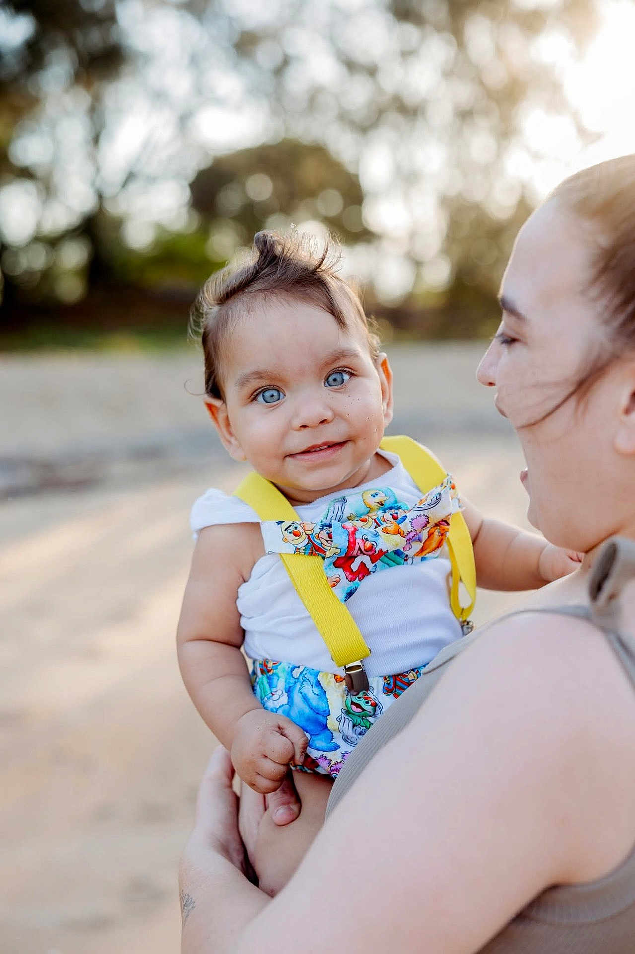 Marcello is registered to the contest to win money with this photo: baby, child, blue_eyes, bowtie, suspenders, smiling, person, adult, outdoor, nature, portrait, holding, happy, cute, daylight, skin, face, clothing, closeup, family