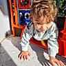 child, toddler, playground, climbing, curly_hair, sunlight, shadow, outdoor, colorful, play_equipment, casual_clothing, fun, active, young, person, daylight, adventure, happy, exploring, nature