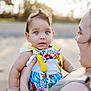 baby, child, blue_eyes, colorful_clothing, bowtie, suspenders, adult_hand, outdoor, sunlight, portrait, holding, skin, expression, cute, person, infant, summer, nature, closeup, happy