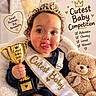 baby, child, toddler, portrait, smiling, tiara, crown, trophy, contest, sash, teddy_bear, stuffed_animal, indoor, seated, cute, cheeks, dessert, food, celebration, text_overlay