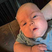 Corbin is registered to the contest to win money with this photo: baby, infant, child, person, arm, tattoo, clothing, indoor, furniture, couch, countertop, face, skin, hand, expression, blur, closeup, holding, portrait, casual