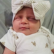 Harper joined the competition — help win amazing prizes! baby, newborn, infant, child, sleeping, portrait, face, smiling, bow, headband, striped, clothing, onesie, blanket, indoors, close_up, adorable, peaceful, lying_down, photography