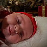 Harper is registered to the contest to win money with this photo: baby, infant, child, face, portrait, red_headband, christmas, holiday, festive, wrapped_gifts, christmas_tree, fairy_lights, white_fur, lying_down, close_up, indoors, soft_lighting, wide_eyes, red_clothing, celebration