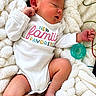 newborn, baby, infant, sleeping, portrait, blanket, white_clothing, onesie, pacifier, fluffy, close_up, face, hands, feet, indoors, family, text_on_clothing, peaceful, candid, cozy