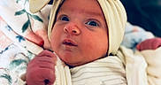 Aria joined the competition — help win amazing prizes! baby, newborn, infant, child, portrait, face, eyes, bow, headband, cream_clothing, onesie, blanket, cozy, lying_down, indoors, soft_lighting, close_up, cute, sleepwear, cuddly
