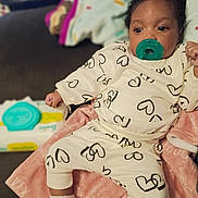 Xya joined the competition — help win amazing prizes! baby, infant, child, portrait, pacifier, onesie, hearts, blanket, sitting, indoors, couch, home, wide_eyed, curly_hair, smiling, clothing, socks, baby_products, soft_blanket, closeup