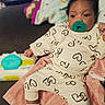 baby, infant, child, portrait, pacifier, onesie, hearts, blanket, sitting, indoors, couch, home, wide_eyed, curly_hair, smiling, clothing, socks, baby_products, soft_blanket, closeup