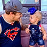 baby, child, man, adult, denim_overalls, blue_bow, hat, cap, smiling, happy, wicker_couch, outdoor, portrait, face, people, casual_clothing, tattoo, interaction, family, cute