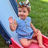 Amirah is registered to the contest to win money with this photo: toddler, child, outdoor, slide, playground, grass, smiling, waving, headband, romper, blue_clothing, barefoot, summer, happy, cute, fun, play, park, daylight, portrait
