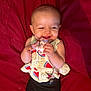baby, smiling, pacifier, yellow_top, watermelon_print, black_pants, red_blanket, happy, child, infant, cute, lying_down, hands, face, portrait, indoors, skin, head, clothing, person