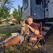 Smoky Veverka joined the competition — help win amazing prizes! man, cat, camping_chair, rv, outdoor, grass, tree, pavilion, sunlight, book, shoes, harley_davidson, leisure, pet, relaxation, nature, summer, daylight, animal, person