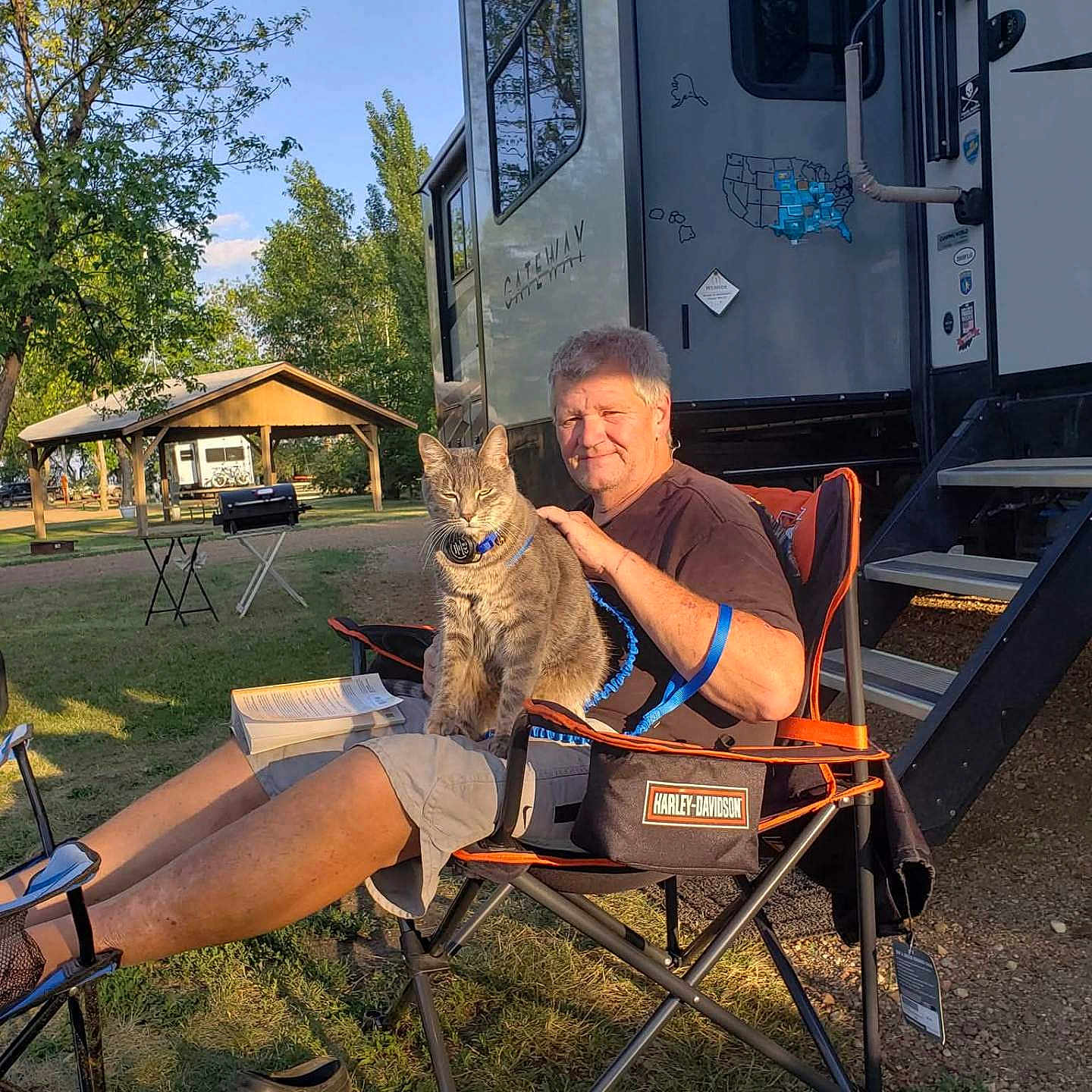 Smoky Veverka joined the competition — help win amazing prizes! animal, book, camping_chair, cat, daylight, grass, harley_davidson, leisure, man, nature, outdoor, pavilion, person, pet, relaxation, rv, shoes, summer, sunlight, tree
