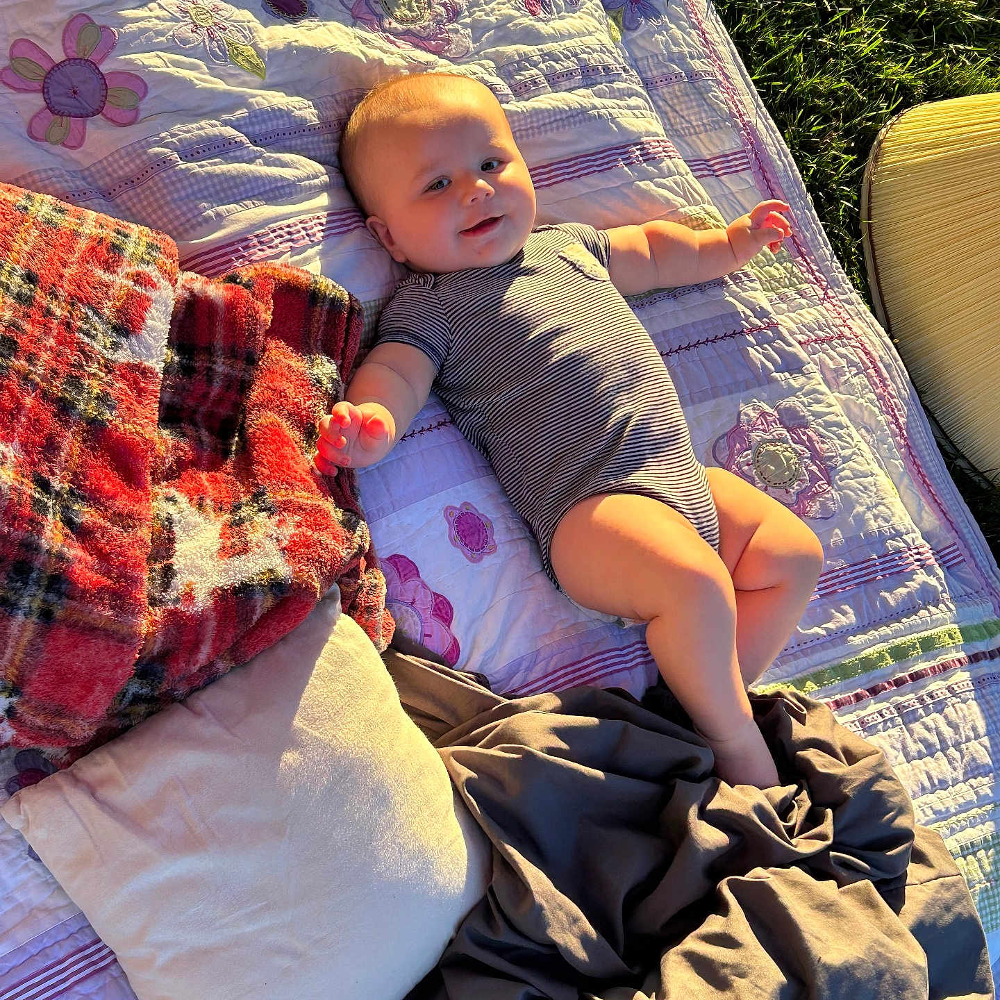 Bruce is registered to the contest to win money with this photo: baby, blanket, child, clothing, cute, grass, happy, infant, lying_down, nature, outdoor, pillow, quilt, relaxing, resting, smiling, soft_texture, striped_onesie, sunlight, warm_light