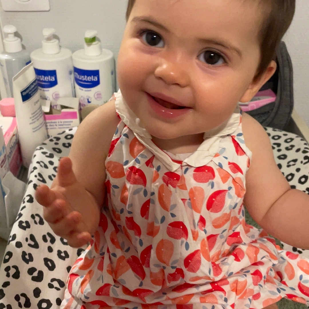 Hénèlya a rejoint le concours — aidez-le/la à gagner de superbes lots ! baby, blanket, bottle, child, closeup, cute, dress, face, hair_clip, happy, indoor, infant, leopard_print, pattern, person, pink, sitting, skincare, smiling, young_child