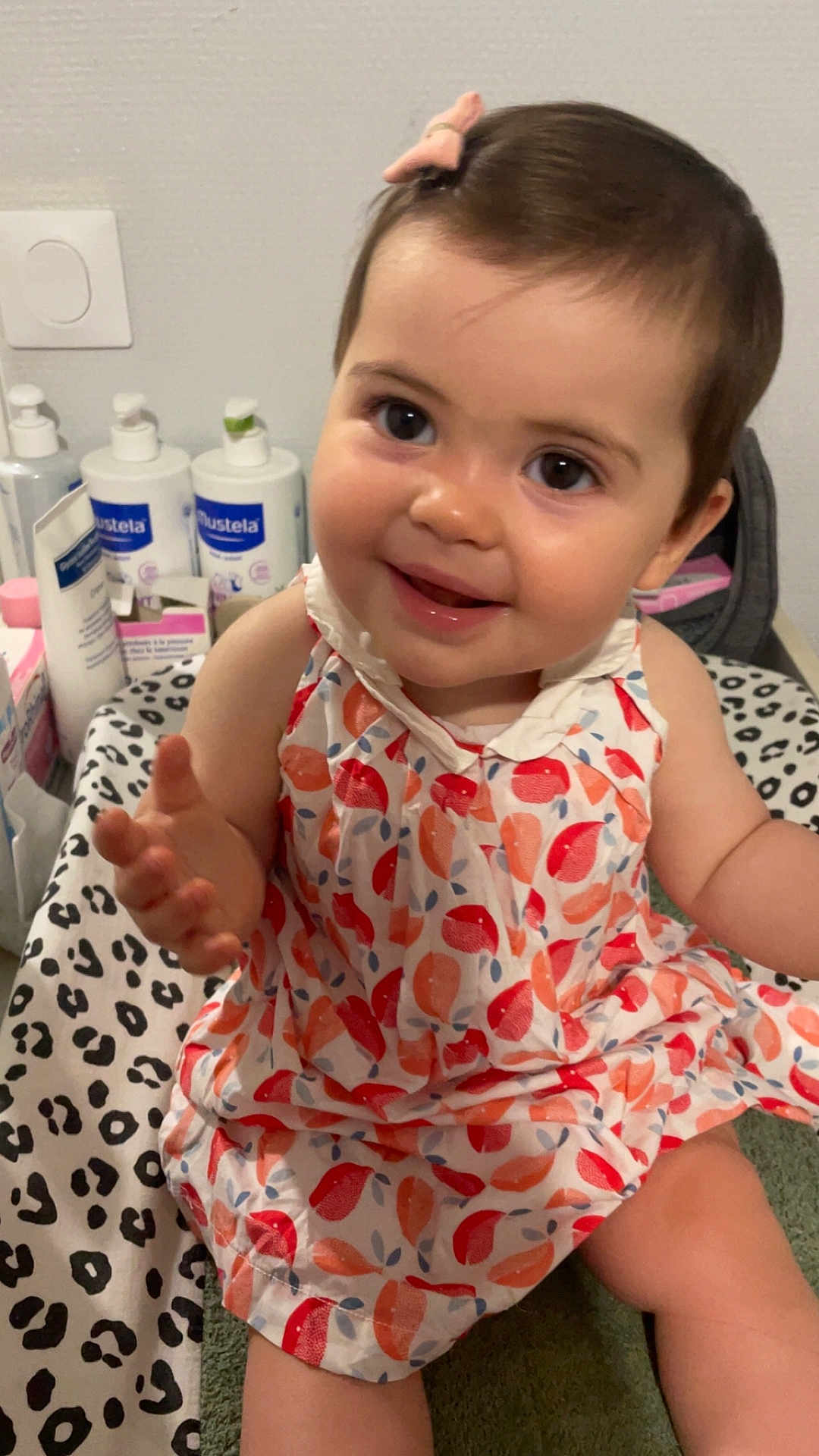 Hénèlya a rejoint le concours — aidez-le/la à gagner de superbes lots ! baby, child, smiling, dress, hair_clip, indoor, leopard_print, blanket, bottle, skincare, face, sitting, cute, person, infant, pink, pattern, happy, young_child, closeup
