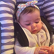 Hénèlya a rejoint le concours — aidez-le/la à gagner de superbes lots ! baby, infant, headband, striped_cushion, toy, hand, face, clothing, seat, bibs, child, cute, young, portrait, indoor, soft_lighting, curious, concentration, baby_girl, floral_pattern