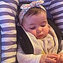 baby, infant, headband, striped_cushion, toy, hand, face, clothing, seat, bibs, child, cute, young, portrait, indoor, soft_lighting, curious, concentration, baby_girl, floral_pattern