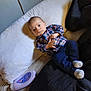 Xavier joined the competition — help win amazing prizes! baby, infant, plaid_shirt, navy_pants, socks, bed, pillow, blanket, lotion_bottle, indoor, person, face, small_child, clothing, resting, curious, wide_eyes, soft_lighting, casual, home