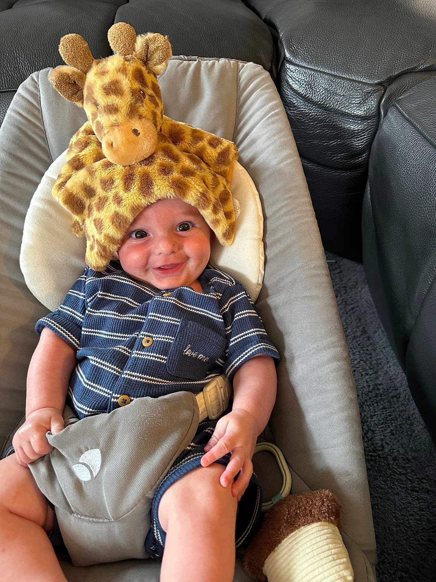 Jordan is registered to the contest to win money with this photo: baby, giraffe_hat, striped_clothing, smile, cushion, baby_seat, stuffed_toy, happy, child, indoor, cute, infant, portrait, comfort, playful, blue, soft_toy, seat_belt, relaxed, cheerful