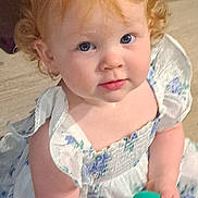 Amalie joined the competition — help win amazing prizes! child, toddler, curly_hair, blue_eyes, white_dress, floral_pattern, toy, indoor, portrait, cute, innocent, baby, person, holding, looking_up, rosy_cheeks, soft_lighting, small_hands, playful, curious