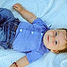 baby, child, infant, blue_shirt, denim_jeans, blanket, outdoor, grass, smiling, portrait, cute, happy, lying_down, young_child, casual_clothing, soft_texture, skin, face, person, relaxed