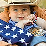 baby, cowboy_hat, bracelet, american_flag, basket, belt_buckle, blue_shirt, smile, face, hand, outdoor, cute, portrait, infant, happy, child, closeup, hat, person, fashion