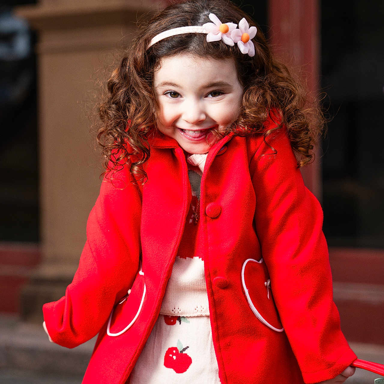Mathilda joined the competition — help win amazing prizes! apple_pattern, child, curly_hair, cute, daylight, fashion, flower_headband, girl, happy, outdoor, person, playful, portrait, red_coat, skirt, smiling, standing, urban, winter_clothing, young