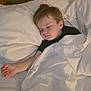 Rexton is registered to the contest to win money with this photo: child, sleeping, bed, blanket, pillow, indoors, cozy, toddler, rest, peaceful, wood, head, face, person, clothing, white, black_shirt, hand, nap, quiet