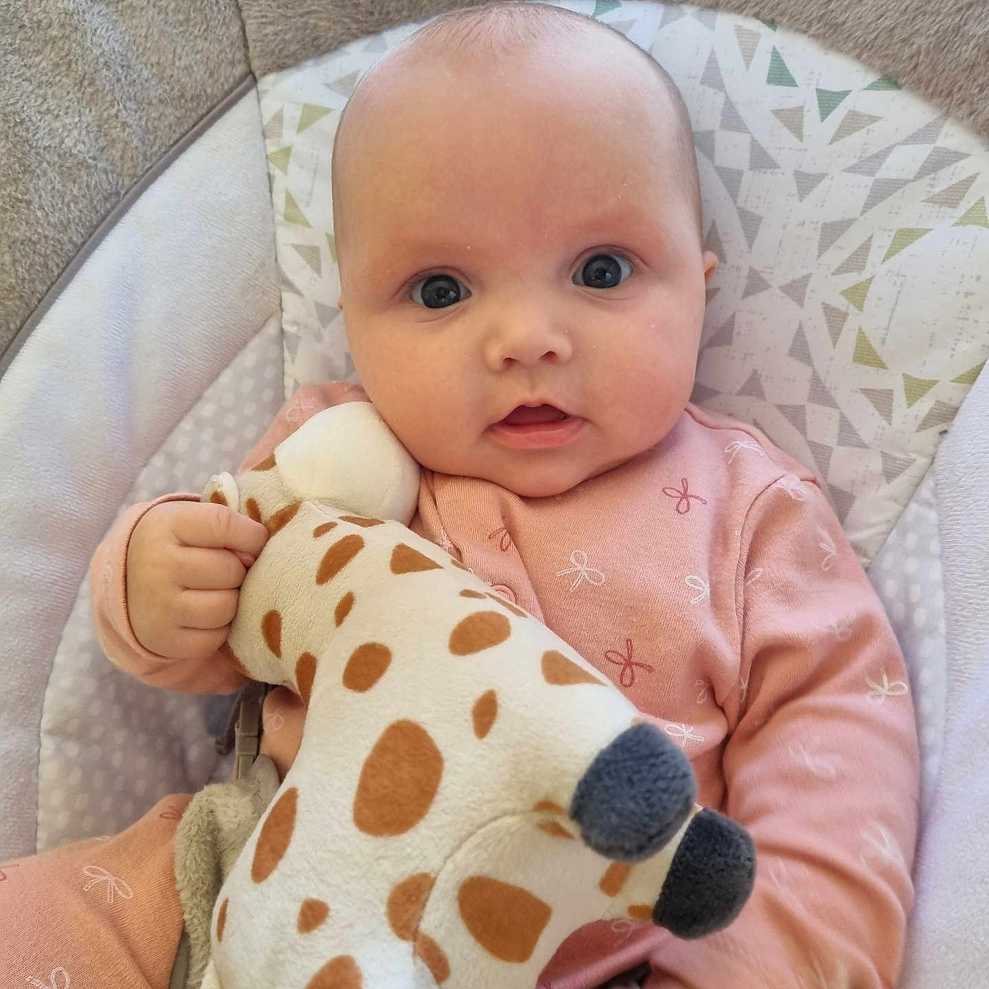 Elsie is registered to the contest to win money with this photo: baby, baby_seat, blue_eyes, child, closeup, comfort, cute, face, giraffe, hand, indoor, infant, looking, newborn, pink_clothing, plush_toy, portrait, seated, soft_texture, toy