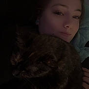 Ruby Willow is registered to the contest to win money with this photo: person, cat, tortoiseshell_cat, blanket, indoor, cozy, closeup, sleeping_cat, face, resting, pet, snuggling, dark_lighting, casual, young_adult, relaxed, home, portrait, comfort, warm