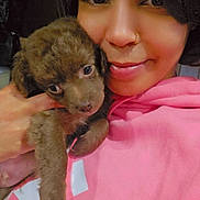 Theodore joined the competition — help win amazing prizes! person, puppy, dog, pet, brown_fur, pink_hoodie, selfie, close_up, nose_ring, smile, holding, cuddling, eyes, face, hand, indoor, portrait, young_adult, cozy, warm_lighting