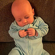 Jordan joined the competition — help win amazing prizes! baby, infant, blue_onesie, sitting, couch, indoor, child, hands, face, head, cute, cozy, focused, texture, clothing, portrait, young, small, human, person