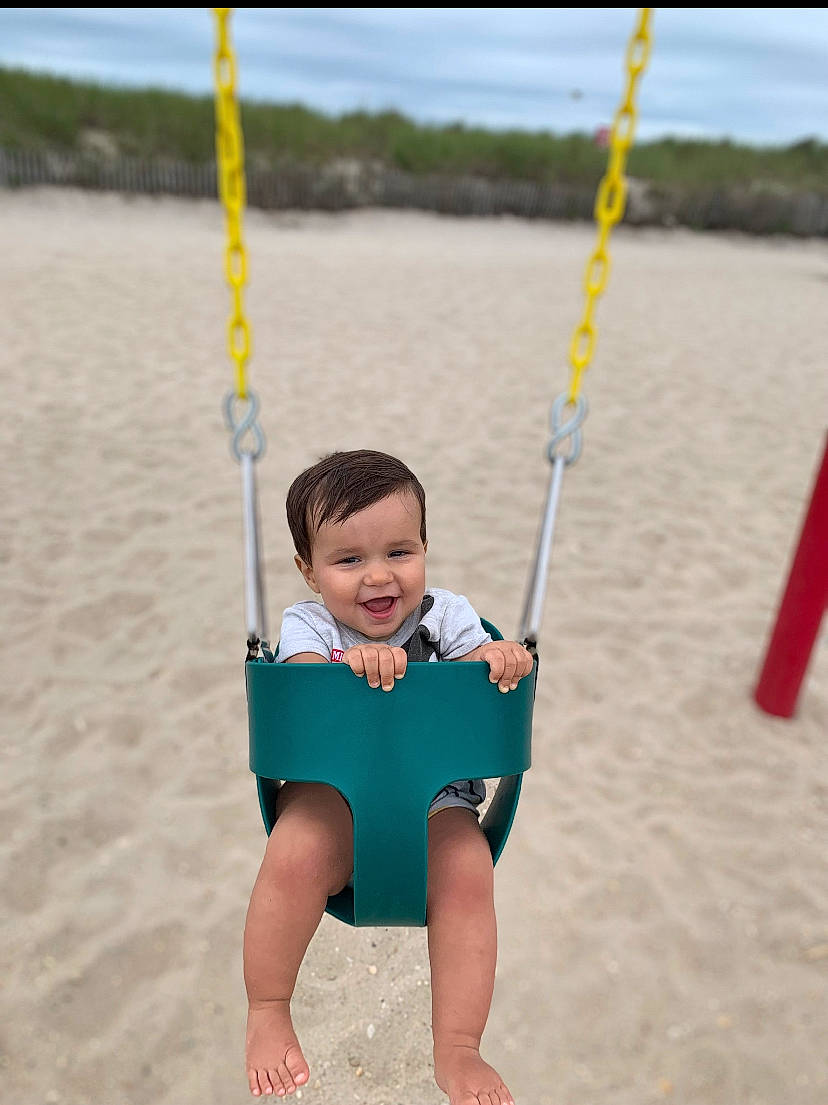 Gavin joined the competition — help win amazing prizes! baby, beach, body_of_water, child, elbow, electric_blue, fun, happy, joy, leisure, person, plant, play, playground, recreation, sand, smile, swing, t_shirt, toddler