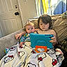 child, baby, tablet, couch, blanket, hello_kitty, indoor, curtains, door, furniture, technology, screen, sitting, siblings, family, cozy, focused, casual, relaxed, play