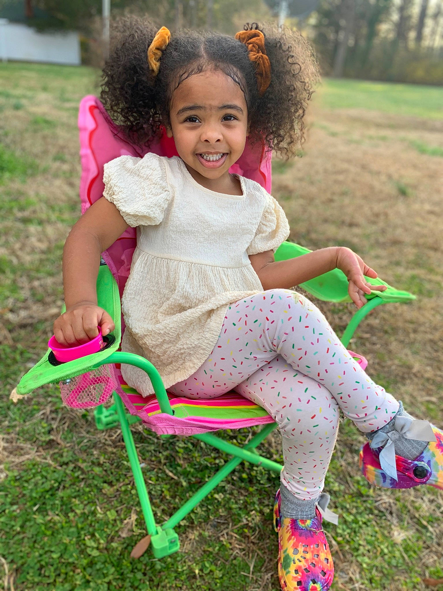 Soleil is registered to the contest to win money with this photo: baby_toddler_clothing, chair, child, dress, eye, face, fun, grass, grass_family, hair, happy, head, joy, leisure, magenta, people_in_nature, person, pink, plant, recreation