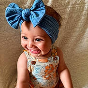 Kehlani is registered to the contest to win money with this photo: baby, child, smiling, headband, blue_bow, floral_outfit, sitting, blanket, cute, happy, portrait, infant, jewelry, bracelet, closeup, indoors, skin, face, expression, adorable