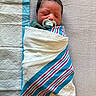 baby, blanket, child, cute, face, head, hospital_pad, indoors, infant, newborn, pacifier, peaceful, person, portrait, resting, sleeping, soft_texture, striped_blanket, swaddled, wrapped
