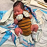baby, baby_clothes, blanket, face, head, hospital_blanket, infant, lying_down, mittens, newborn, pacifier, pencil, person, resting, skin, sleeping, socks, soft_toys, striped_onesie, tiny