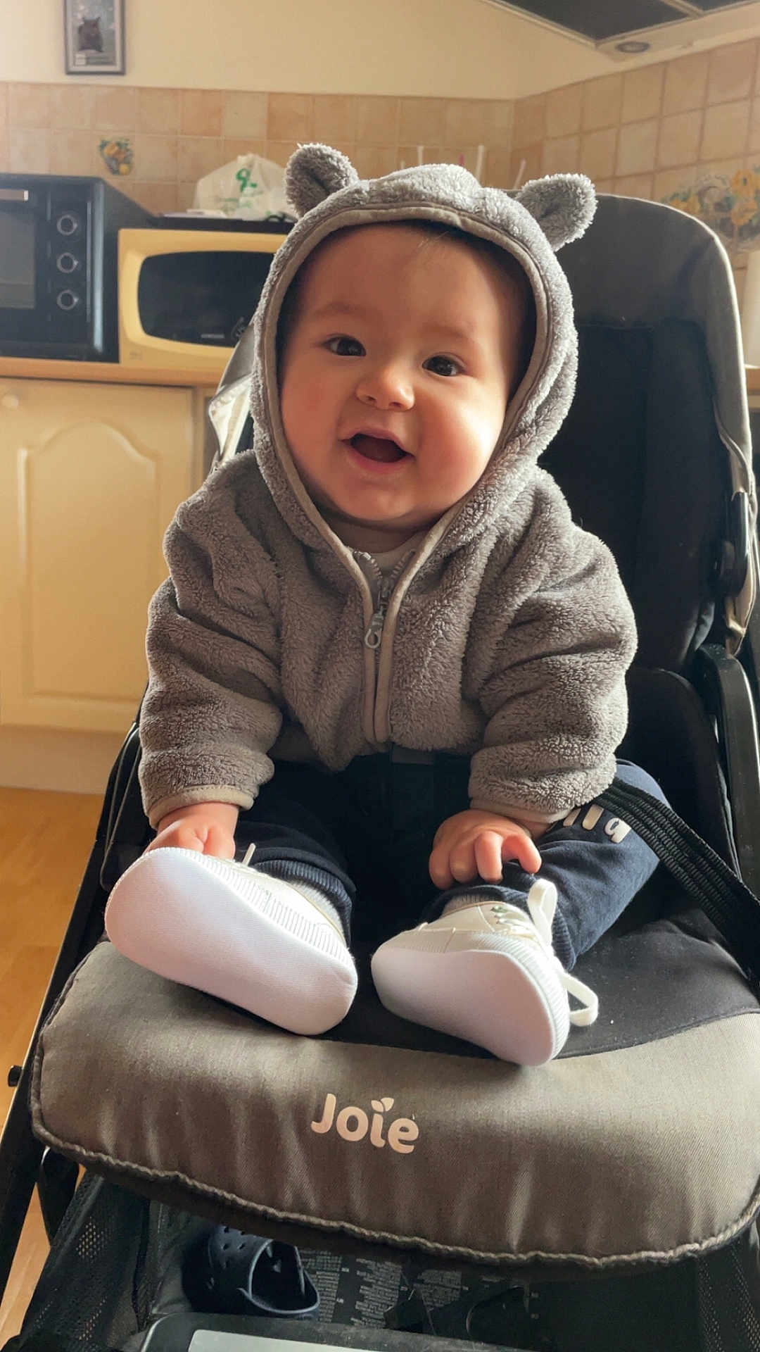 Maé participe au concours pour gagner de l'argent avec cette photo : baby, child, stroller, hoodie, smiling, indoor, white_shoes, cute, face, person, seated, clothing, happy, infant, furniture, black_stroller, toy, footwear, babywear, warm_clothing